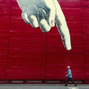 Man walking down a city street in front of some art.