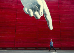 Man walking down a city street in front of some art.