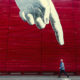 Man walking down a city street in front of some art.