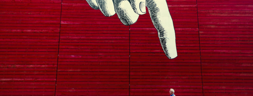 Man walking down a city street in front of some art.