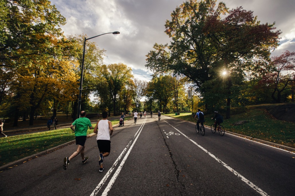 People running, walking and cycling on a tree-lined road