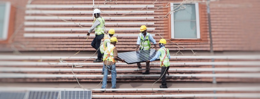 Workers in hard hats installing solar panels