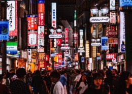 Night shot of a crowded street in Tokyo full of neon signs.