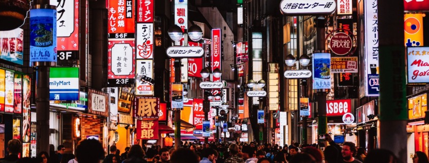 Night shot of a crowded street in Tokyo full of neon signs.